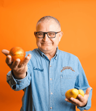 Leo holding nectarine and mango in front of orange background