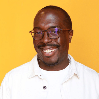Charles smiling in front of orange background